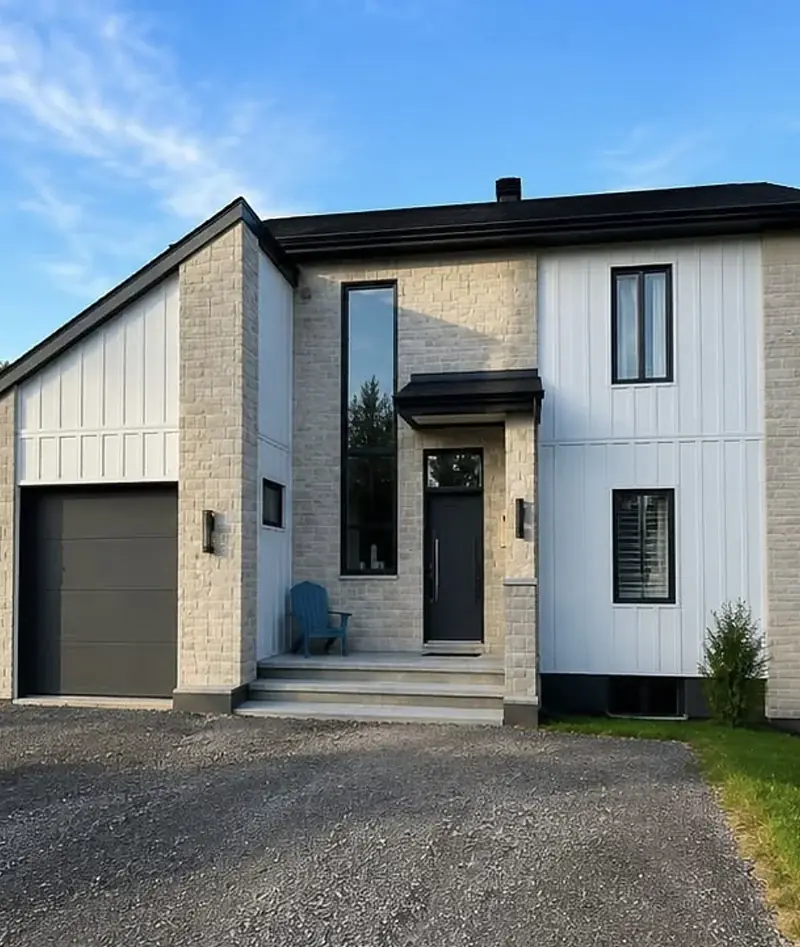 Maison unifamiliale terminée avec façade de pierre claire et revêtement vertical blanc